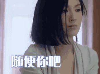 a woman with short black hair is looking at the camera with chinese writing behind her .