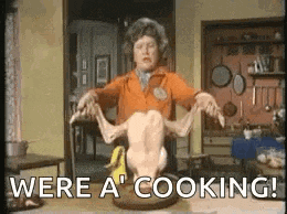 a woman is holding a dead chicken on a table in a kitchen .