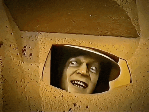 a man 's face is sticking out of a hole in the wall