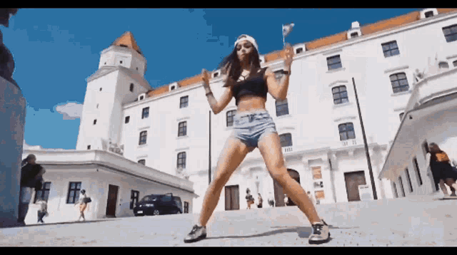 a woman in shorts is dancing in front of a building