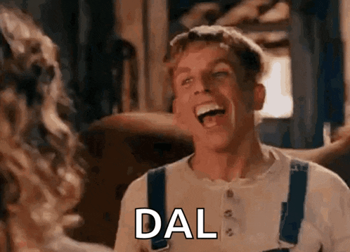 a man in overalls is laughing while talking to a woman in a movie .