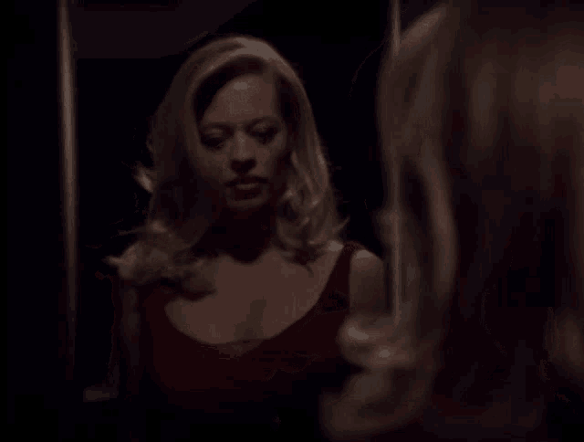 a woman in a red dress is looking at herself in the mirror