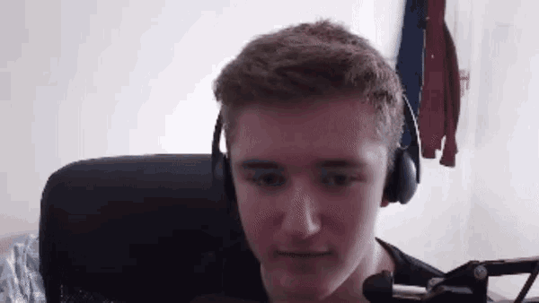 a young man wearing headphones looks at the camera