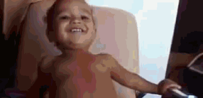 a baby is smiling while sitting in a chair .