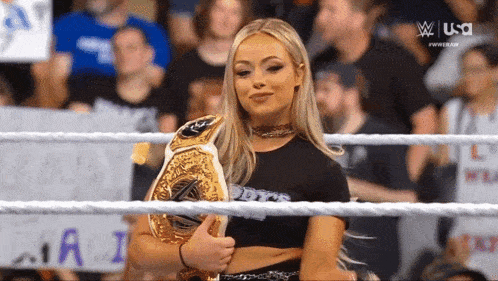 a woman in a wrestling ring holding a championship belt with the usa logo in the background
