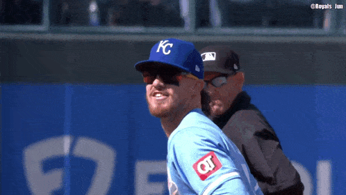 a baseball player wearing a kc hat and sunglasses is smiling