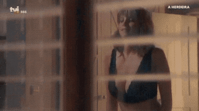 a woman in a bra is looking out a window .