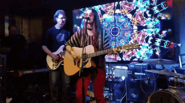 a woman singing into a microphone while playing an acoustic guitar