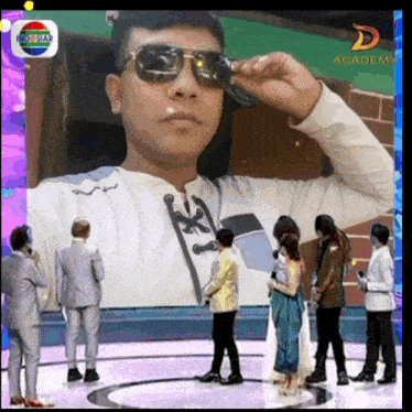 a man wearing sunglasses stands in front of a screen that says academy