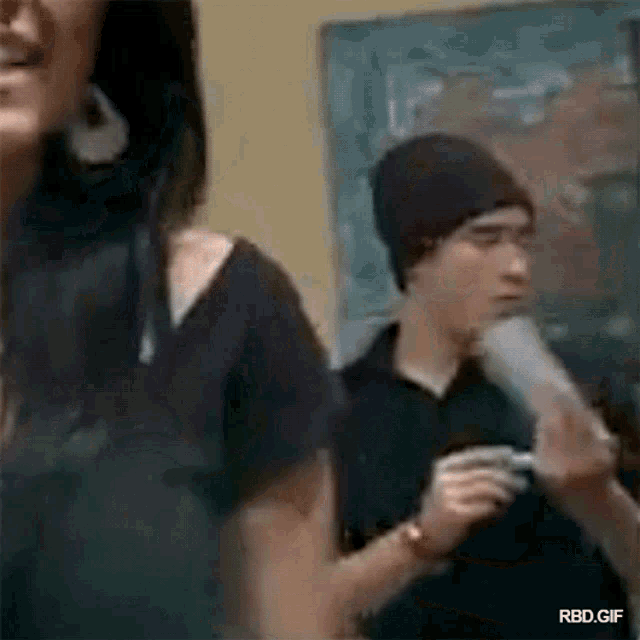 a man and a woman are standing next to each other in a room . the woman is wearing a black beanie .