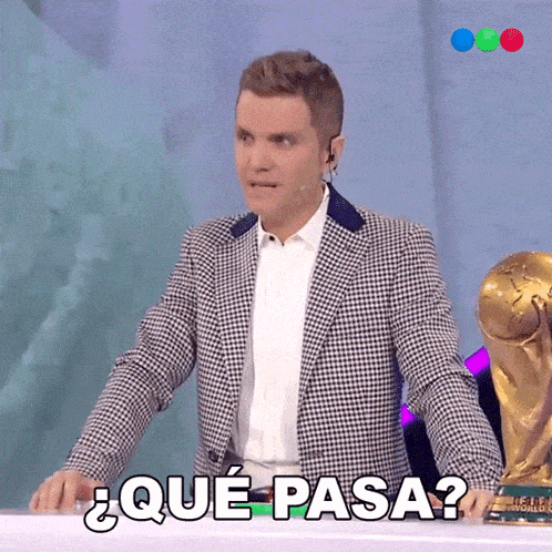a man in a plaid suit stands in front of a trophy and says " que pasa "