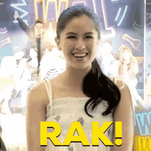 a woman is smiling in front of a sign that says rak on it
