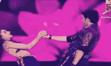 a man and a woman are kissing on a stage in front of a purple background .