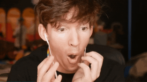 a man with a surprised look on his face is holding a pair of ear buds