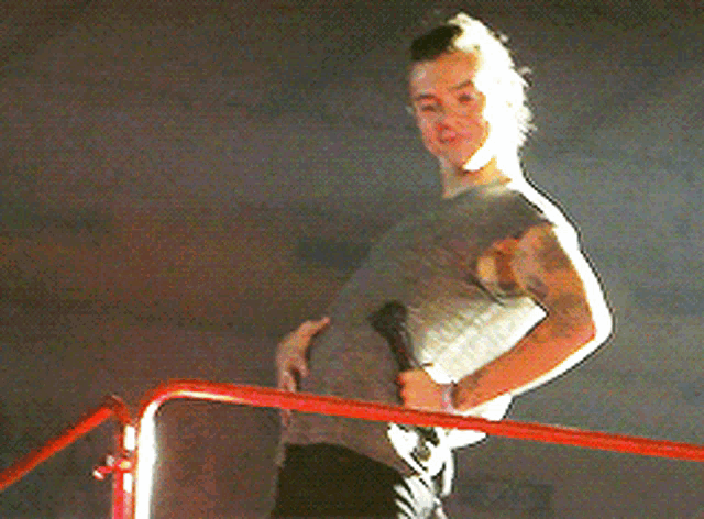 a man with a tattoo on his arm stands on a red railing