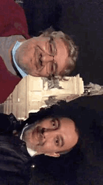two men standing next to each other with a statue behind them