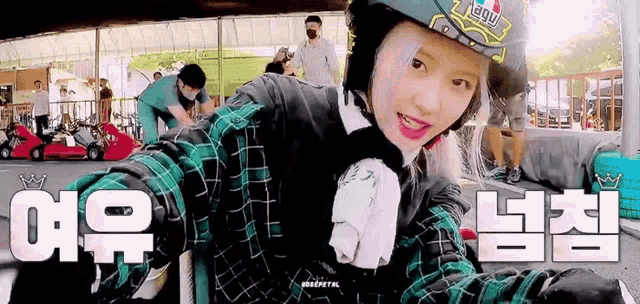 a girl is wearing a helmet and a plaid shirt while riding a go kart .