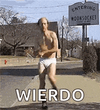 a shirtless man in underwear is running down a sidewalk in front of a sign that says entering woonsocket .