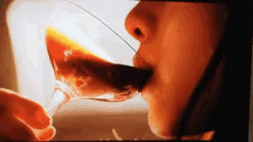 a woman is drinking from a glass with her tongue out