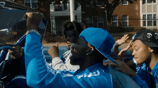 a man wearing a blue jacket that says ' free ' on it is driving a car