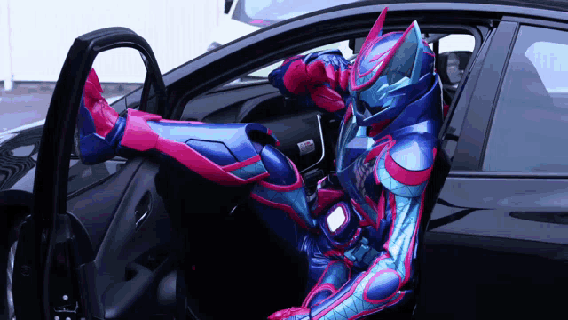 a person in a superhero costume sits in the driver 's seat of a car