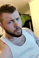 a man with a beard wearing a white tank top is making a funny face