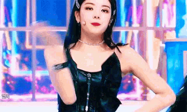 a woman is standing on a stage wearing a black leather top and a choker .