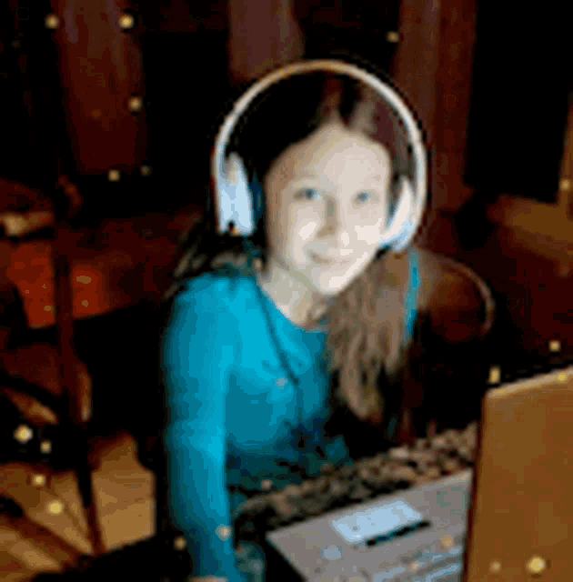 a young girl wearing headphones is sitting in front of a laptop computer .