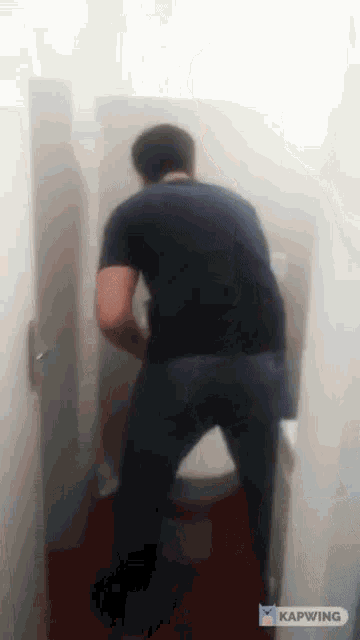 a man is urinating on a toilet in a bathroom .