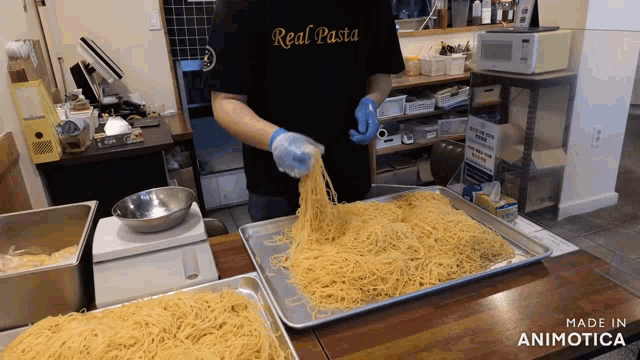 a man wearing a black shirt that says real pasta is preparing spaghetti