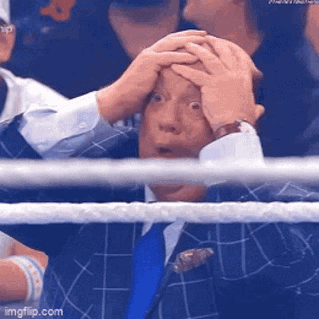 a man in a suit and tie is holding his hands to his head