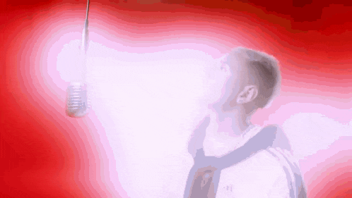 a man singing into a microphone with a red background behind him