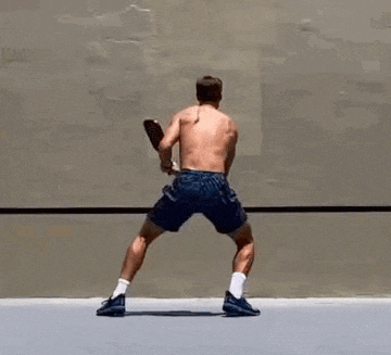 a shirtless man is playing ping pong with a paddle .