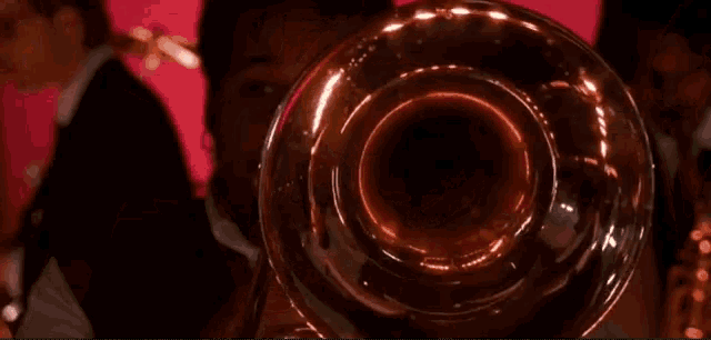 a man is playing a trombone in front of a red wall