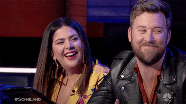 a man and a woman are sitting next to each other and the man is wearing a leather jacket .