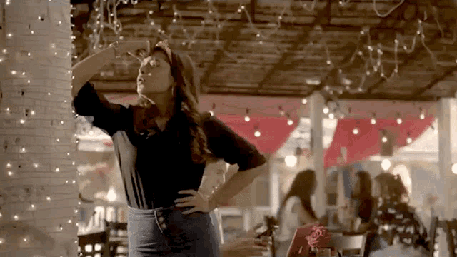 a woman in a black shirt stands in a restaurant with her hands on her hips