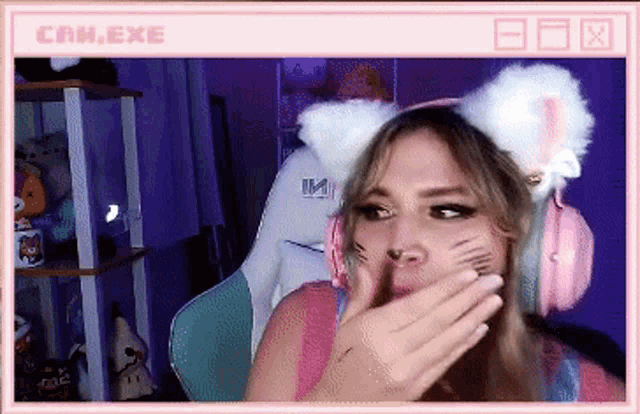 a woman wearing cat ears and headphones is covering her mouth with her hand
