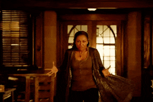 a woman is standing in a room with her arms outstretched and making a funny face .