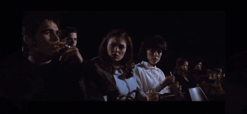a group of people are sitting in a dark room watching a movie .