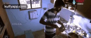 a man is cooking in a kitchen with a pot and a pan .