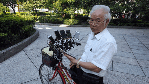 a man standing next to a bicycle with a basket full of phones on it