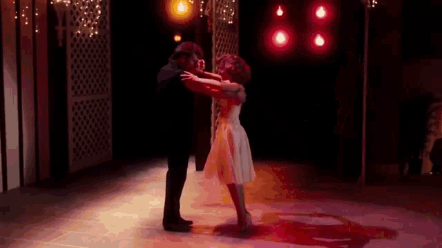 a man and woman are dancing together on a dance floor in a dark room .