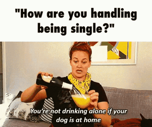 a woman is sitting on a couch holding a glass of orange juice and a bottle of wine ..