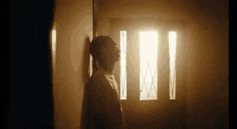 a man is leaning against a wall in a dark room in front of a door .