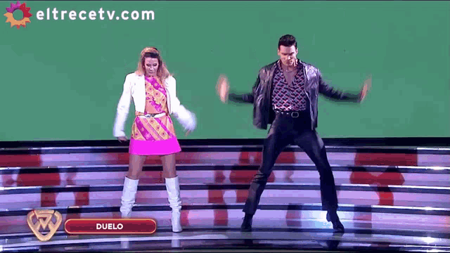 a man and a woman are dancing on a stage with duelo written on the bottom
