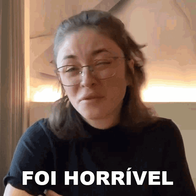 a woman wearing glasses and a black shirt with the words foi horrivel on the bottom right