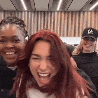 a woman with red hair is laughing while wearing a new york yankees hat