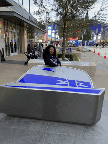 a woman sits on a bench in front of a building that has the letter w on it