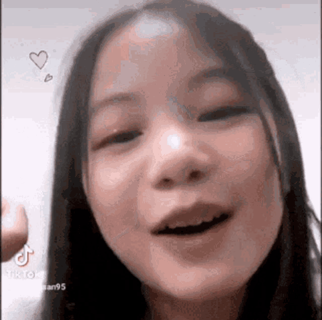 a close up of a young girl making a funny face with a heart above her head .