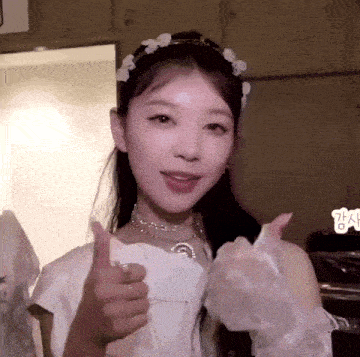 a woman in a white dress and gloves is giving a thumbs up sign .